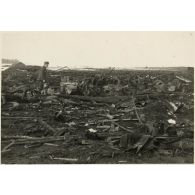 [Un soldat constate les dégâts causés par un bombardement, au centre un side-car].