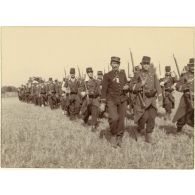 La marche en colonne par quatre. Il fait chaud. Le soleil tape sur les nuques. Très débraillés, les képis en bataille, les pioupous chantent, l'air très crâne.