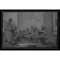 [Repas de militaires assis contre un mur].