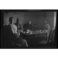 [Portrait d'une famille paysanne attablée dans un intérieur, avec un militaire].