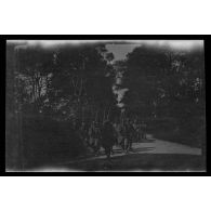 [Colonne de soldats militaires sur une route ombragée].
