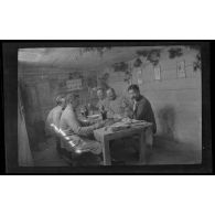 [Militaires attablés à l'intérieur d'une baraque].