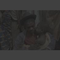Portrait d'un homme âgé tenant dans ses bras un enfant en pleurs portant des cicatrices sur la nuque et un vêtement tâché à Kibeho.