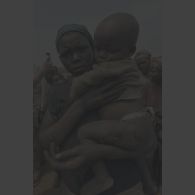 Une femme porte dans ses bras un petit enfant présentant des meurtrissures à la cuisse à Kibeho.