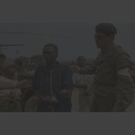 Un médecin principal de l'élément militaire médical d'intervention rapide (EMMIR) accompagne un homme blessé, au bras mutilé et à l'oreille fendue, à Kibeho.