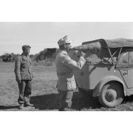 Un lieutenant (Oberleutnant) donne des ordres à l'aide d'un porte-voix près d'un homme de troupe et d'une voiture Kfz-1.