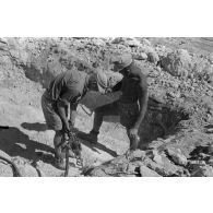 Des sapeurs du Génie allemand creusent le sol à l'aide d'un marteau-piqueur.