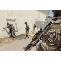 Des stagiaires irakiens fouillent un élément dangereux sous la supervision d'un instructeur français à Bagdad, en Irak.