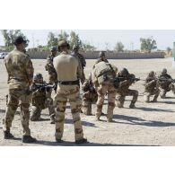 Des instructeurs encadrent une séance de tir au fusil d'assaut auprès de stagiaires irakiens sur un champ de tir à Bagdad, en Irak.