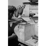 Un homme d'équipage casse des oeufs sur la plaque d'un casier extérieur du Panzer II et les fait cuire.