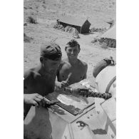 Un homme d'équipage casse des oeufs sur la plaque d'un casier extérieur du Panzer II et les fait cuire.