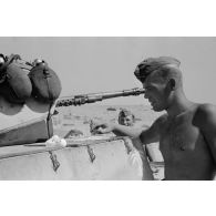 Un homme d'équipage casse des oeufs sur la plaque d'un casier extérieur du Panzer II et les fait cuire.