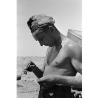 Un soldat allume sa cigarette à l'aide d'une loupe.