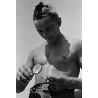 Un soldat allume sa cigarette à l'aide d'une loupe.