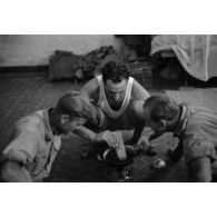 Trois hommes font cuire de la nourriture dans une pièce.