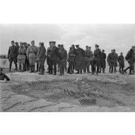 Le groupe d'officiers inspecte une position d'artillerie, il pourrait s'agir d'une position de télémètre camouflée sous un filet.