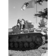 A l'issue d'une prise d'armes, un pilote de char monte à bord du Panzer III.