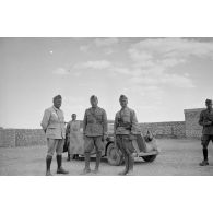 A l'intérieur du fort de Mechili, des officiers italiens, dont un officier général, posent puis parlent devant une voiture Fiat.
