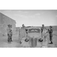 A l'intérieur du fort de Mechili, des officiers italiens, dont un officier général, posent puis parlent devant une voiture Fiat.