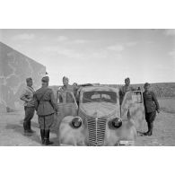 A l'intérieur du fort de Mechili, des officiers italiens, dont un officier général, posent puis parlent devant une voiture Fiat.