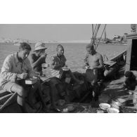 Des soldats italiens mangent sur le pont d'un bateau.