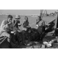 Des soldats italiens mangent sur le pont d'un bateau.