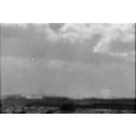 Le groupe d'officiers observe à la jumelle les combats. Impacts d'artillerie dans le désert (image floue).