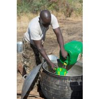 Un soldat malien verse de l'huile dans une marmite pour la préparation de l'ordinaire en bivouac sur le camp de Koulikoro, au Mali.