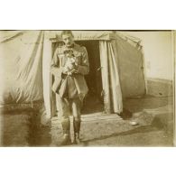 [Militaire posant à l'entrée d'une tente avec un chiot, s.d.]