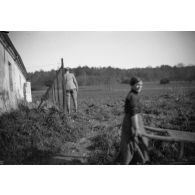 [Jeune femme passant dans un champ dans lequel se promène un soldat, s.d.]