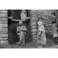 [Un soldat, une femme et un enfant posent devant un muret, s.d.]