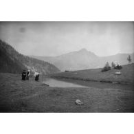 [Trois femmes au bord d'un cours d'eau en montagne, s.d.]