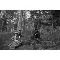[Deux femmes et un chasseur alpin assis dans une forêt, s.d.]