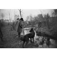 [Deux enfants au bord d'un cours d'eau avec un chien, s.d.]