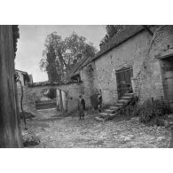 [Un homme et un enfant posent devant un ancien bâtiment de village, s.d.]