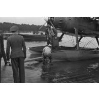 Un pilote d'hydravion Arado Ar-95 descend de son appareil, une mallette à la main, des officiers de la Luftwaffe l'attendent.