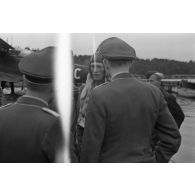 Un pilote d'hydravion Arado Ar-95 descend de son appareil, une mallette à la main, des officiers de la Luftwaffe l'attendent.