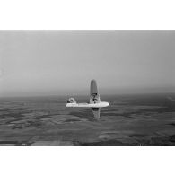 Un planeur monoplace de type DFS Habicht, du N.S.F.K. (Nationalistischen Flieger-Korps) en vol au dessus d'un paysage agricole allemand.