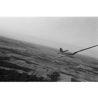 Un planeur monoplace de type DFS Habicht, du N.S.F.K. (Nationalistischen Flieger-Korps) en vol au dessus d'un paysage agricole allemand.