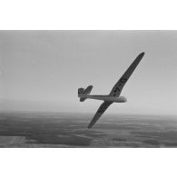 Un planeur monoplace de type DFS Habicht, du N.S.F.K. (Nationalistischen Flieger-Korps) en vol au dessus d'un paysage agricole allemand.
