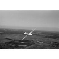 Un planeur monoplace de type DFS Habicht, du N.S.F.K. (Nationalistischen Flieger-Korps) en vol au dessus d'un paysage agricole allemand.