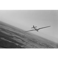 Un planeur monoplace de type DFS Habicht, du N.S.F.K. (Nationalistischen Flieger-Korps) en vol au dessus d'un paysage agricole allemand.