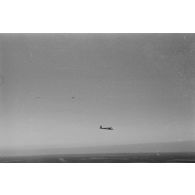 Un planeur monoplace de type DFS Habicht, du N.S.F.K. (Nationalistischen Flieger-Korps) en vol au dessus d'un paysage agricole allemand.