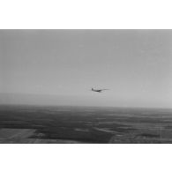 Un planeur monoplace de type DFS Habicht, du N.S.F.K. (Nationalistischen Flieger-Korps) en vol au dessus d'un paysage agricole allemand.