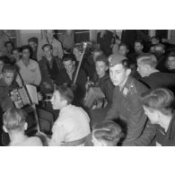 Des jeunes membres du N.S.F.K. chantent et jouent de la musique. Au milieu d'eux, une jeune recrue de la Luftwaffe.