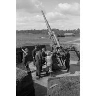 Mise en batterie d'une pièce de 8,8-cm-FlaK-18-L56, placée dans un abri en bois.