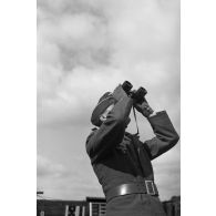 Un Leutnant de la DCA de l'armée de l'air allemand (FlaK) aux jumelles et donne des indications de direction à des servants de télémètre.