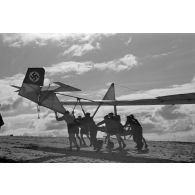 Des jeunes membres du Nationalsozialistischen Flieger-Korps (N.S.F.K.) acheminent un planeur léger sur son aire d'envol.