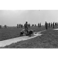 Deux membres des Hitlerjugend installent un modéle réduit d'avion sur son aire de décollage, sous la surveillance d'un Truppführer du N.S.F.K.