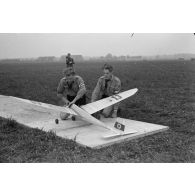 Deux membres des Hitlerjugend installent un modéle réduit d'avion sur son aire de décollage, sous la surveillance d'un Truppführer du N.S.F.K.